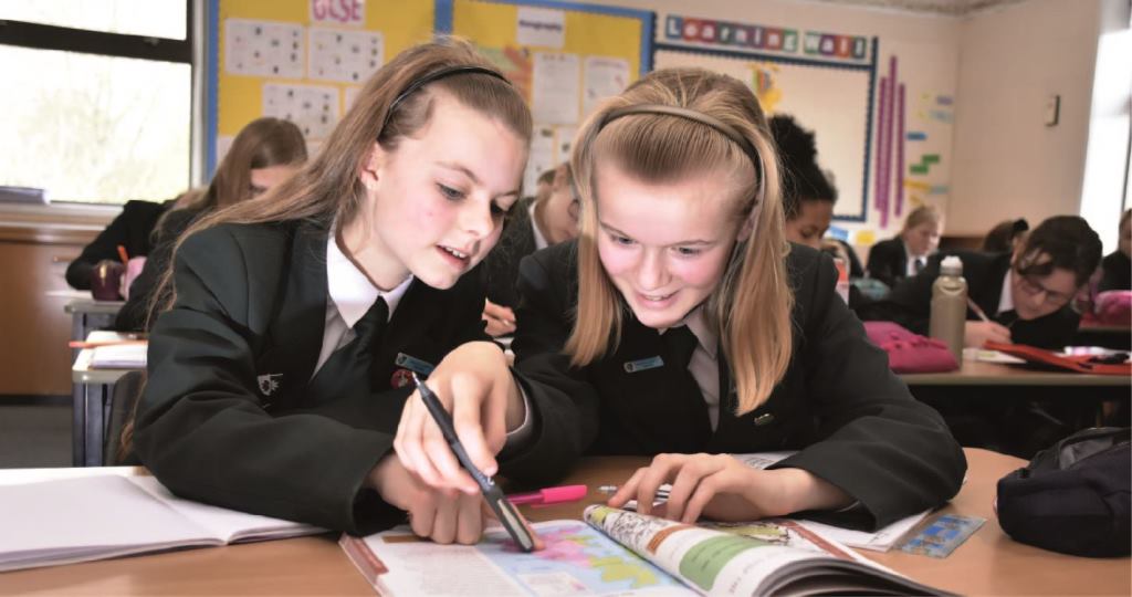 Two students working at a desk in class