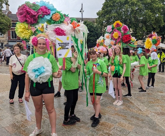 group of students in rain with paper flowers