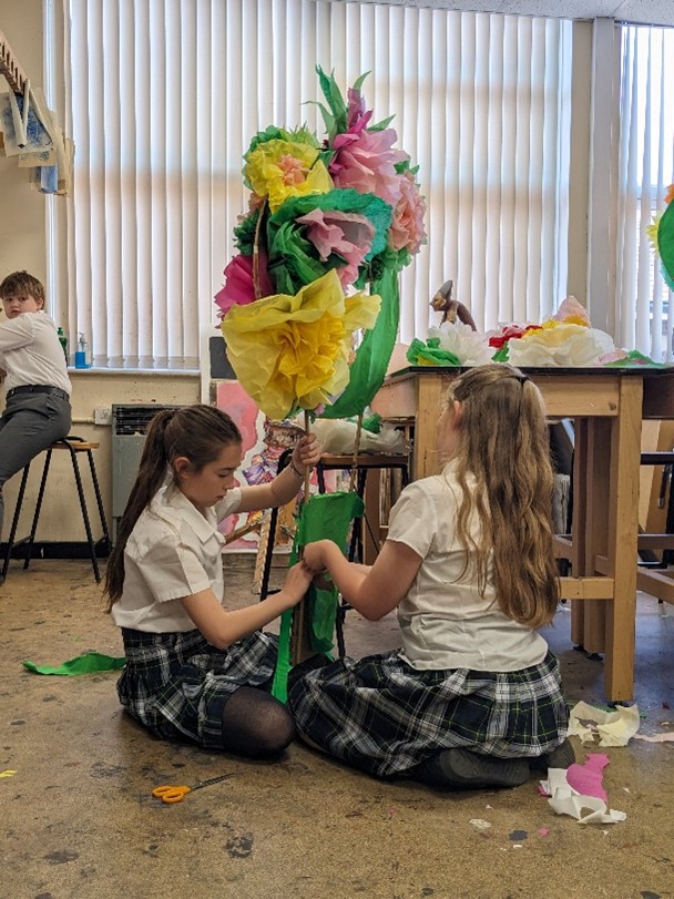 students sitting on floor making paper flowers