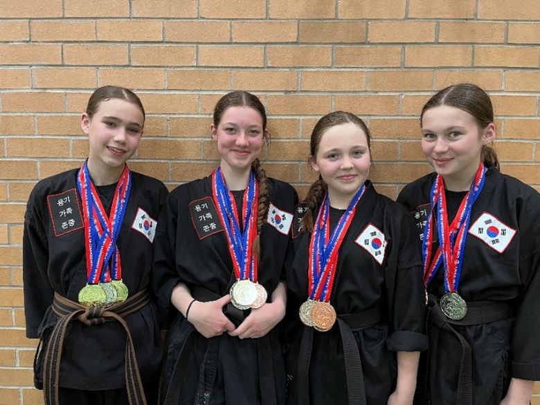 4 students proudly showing their martial art medals