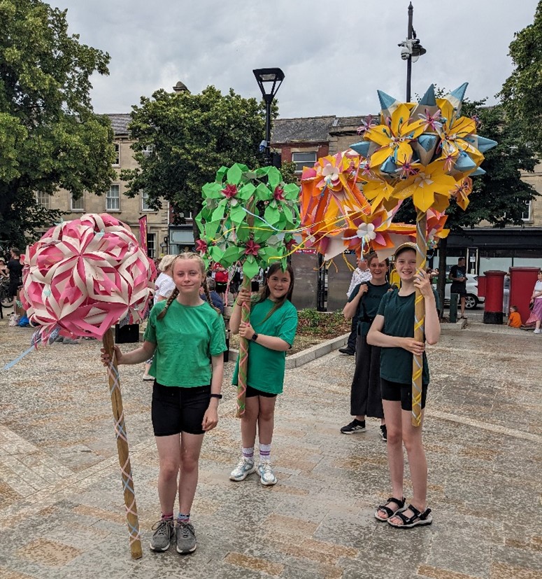 students in rain with paper flowers