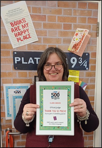 Librarian holding up a 500 words judge poster 